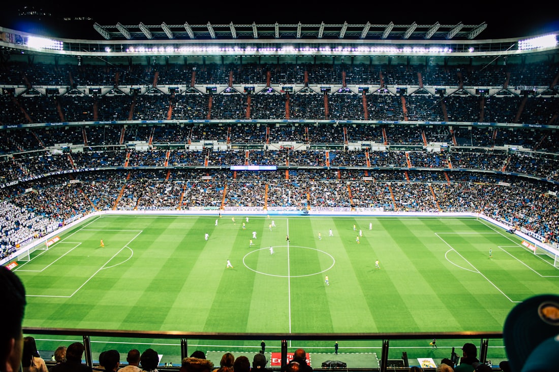 Stadion sepak bola dengan lampu sorot menyala saat pertandingan malam